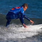 "mavi dalış kıyafetli adam dalga üstünde sörf yapıyor."